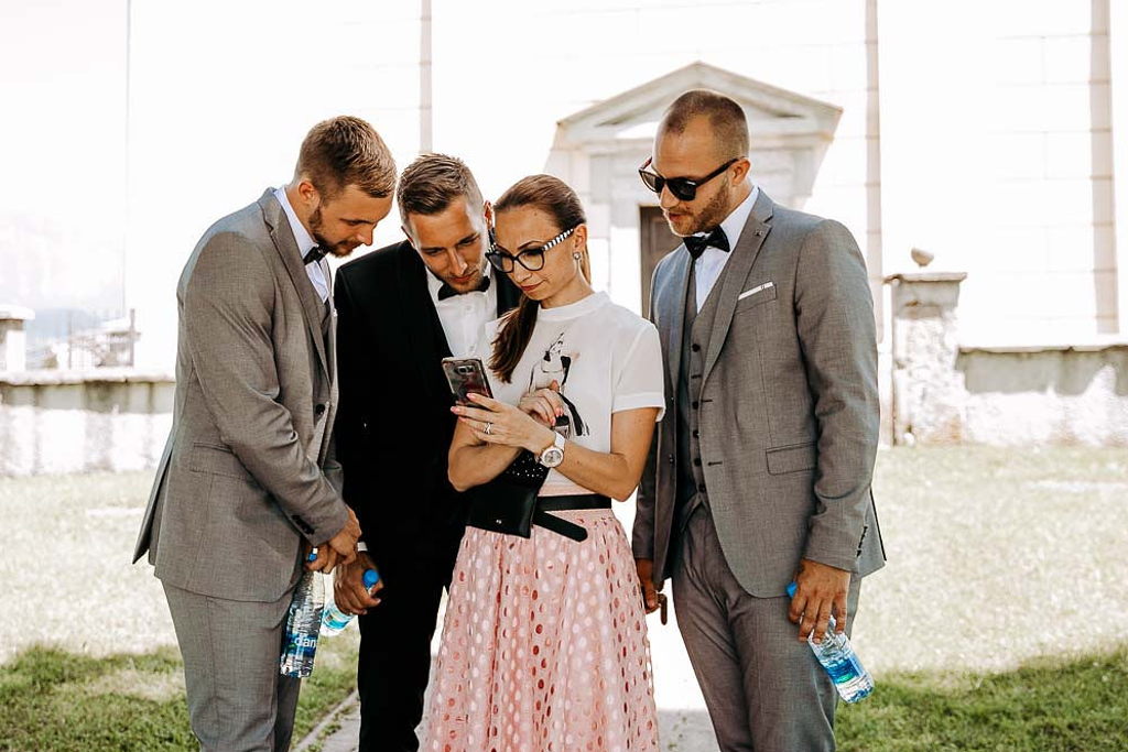 Ženin s pričama gleda v poročni protokol, ki ga v rokah drži izkušena organizatorka porok Petra Starbek iz poročne agencije Storija weddings. Foto: Tamara Vidmar Photography