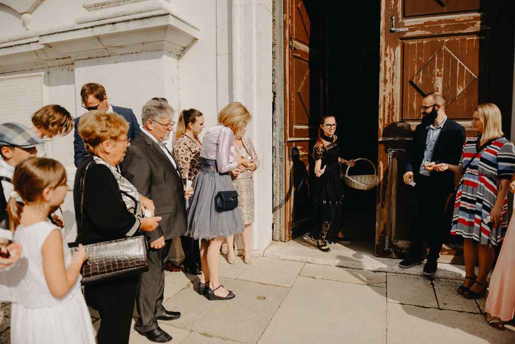 Načrtovalka porok Petra Starbek med cerkvenimi vrati sporoča svatom, da prihajata nevesta in ženin. Foto: Moj Fokus Photography