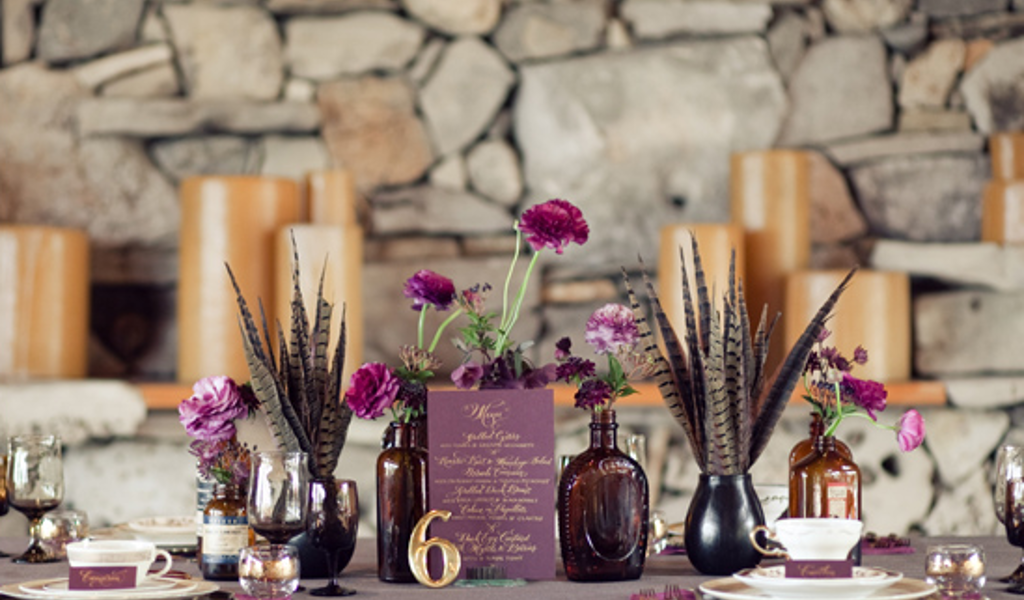 Poročno omizje z zlato številko mize 6. Poročno mnizo krasi dekoracija v vijola barvi, kozarci, svečke ter zlat poročni pribor. Foto:  The Nichols Photography