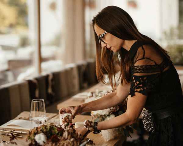 Petra Starbek med pripravljanjem poročne mize v boho stilu. Pri organizaciji porok vedno poskrbi, da so vsi poročni detajli (cvetlični obok, sveče, vrtne lučke…) na svojem mestu.