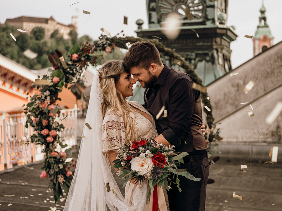 Ženin in nevesta pred okroglim cvetličnim obokom. Nevesta drži v rokah čudovit poročni šopek cvetličarke Khaye. Vse skupaj je pripravila načrtovalka porok Petra Starbek, ki ima veliko znanja, izkušenj in poznanstva s področja porok.