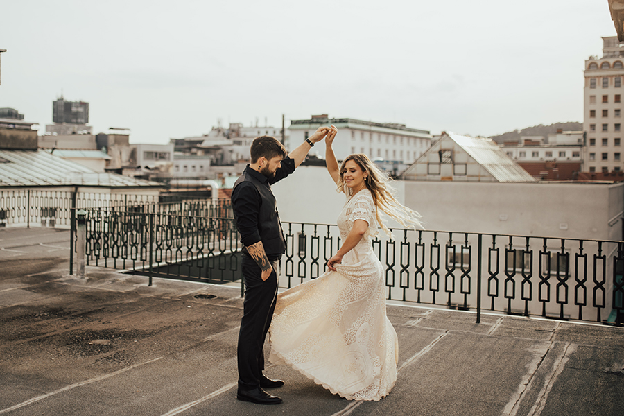 Poročni par po simboličnem civilnem obredu zadovoljno pleše na strehi hotela Union v Ljubljani. Za najboljše poročne ponudnike, ki se ujamejo z vsakim parom, je poskrbela agencija Storija weddings.